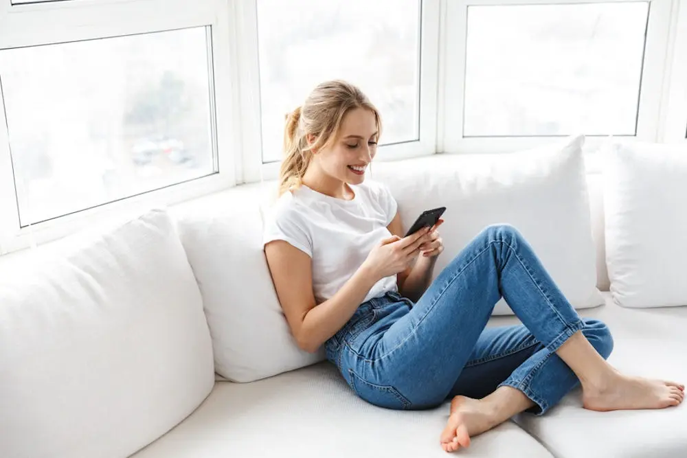 technology-in-addiction-recovery a woman sitting on couch while using her phone