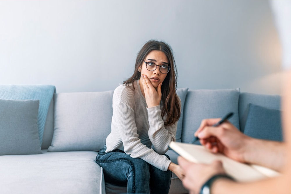 Woman sharing personal struggles during a one-on-one therapy session centered on harm reduction vs abstinence