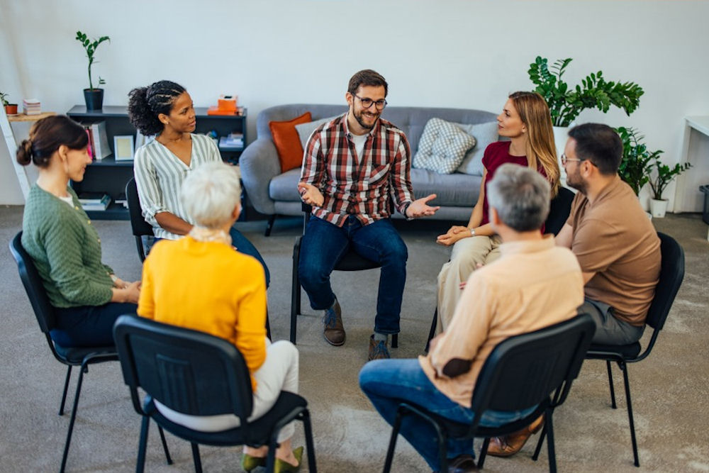 Facilitator leads a therapy session focused on harm reduction vs abstinence in substance use treatment
