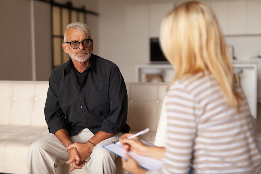 Therapist talking with fathers in recovery, older man listening seriously during a counseling session