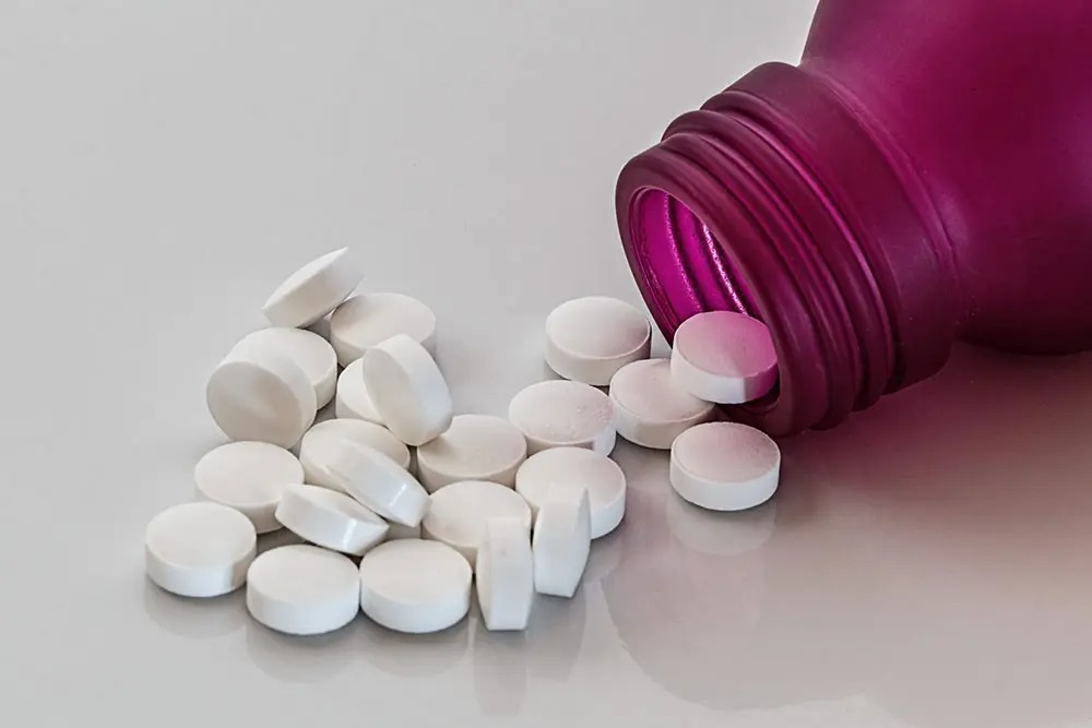 White tablets on table representing the question is kratom an opioid.