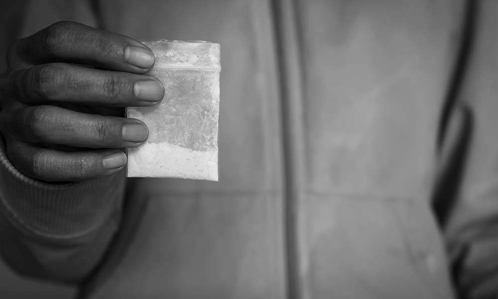 A person holds a clear plastic bag containing white powder of meth